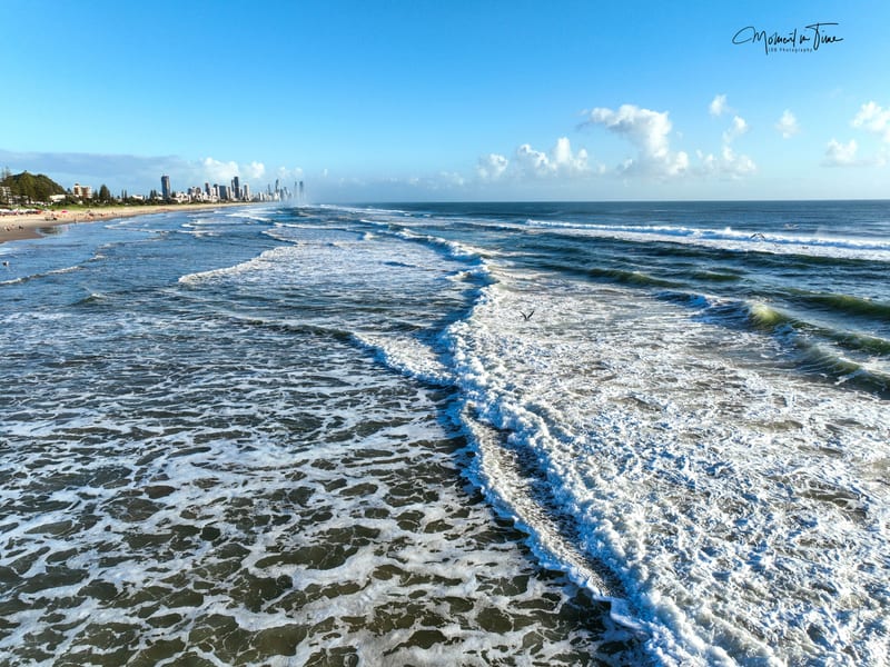 Surfers Paradise beach at sunset with Gold Coast skyline reflected in wet sand
